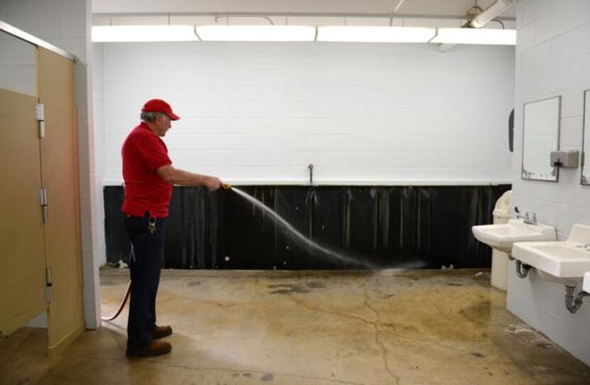 Jones sprays down the men's restroom. As part of the renovations, the troughs will be...