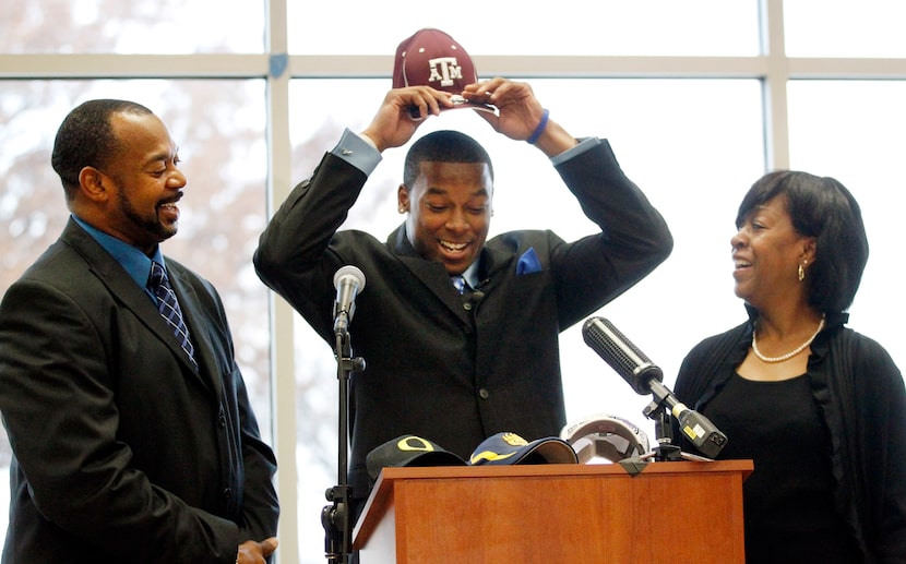 Skyline High wide receiver Thomas Johnson (center) puts on a Texas A&M cap, as father Robert...