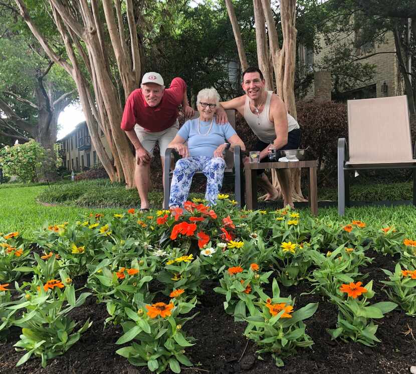 Gary Graham (left) and Jeffrey Michael help neighbor Jane Barker with planting flowers.