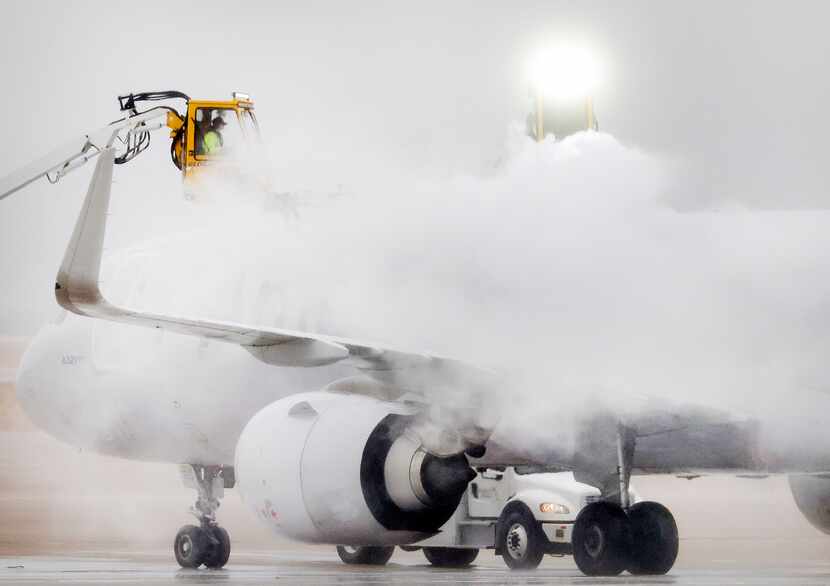 El personal de American Airlines trata de eliminar el hielo de un avión para que pueda...