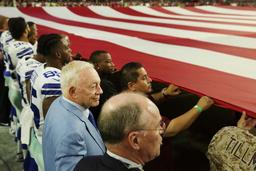 Dallas Cowboys owner Jerry Jones stand locked in arms with players and and other team...