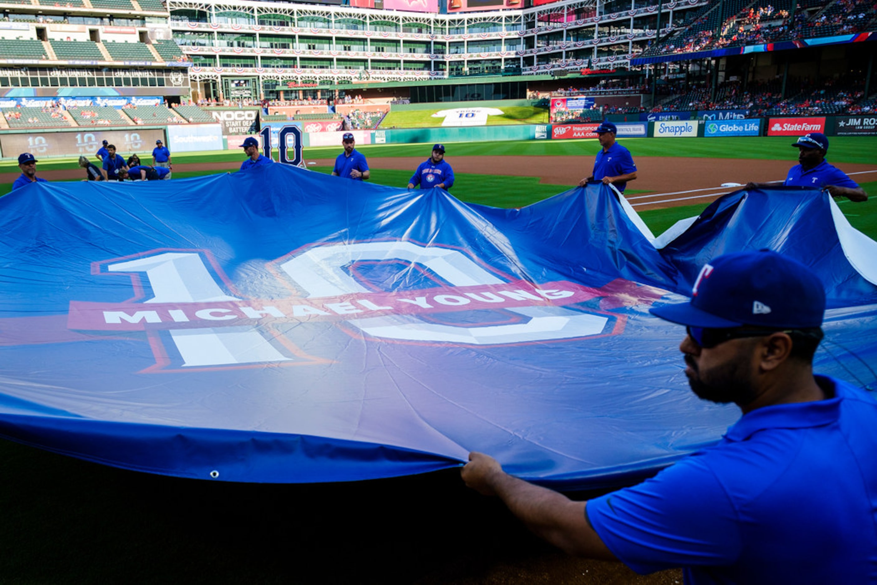 Groundskeeper position a tarp bearing Michael YoungÃs number before ceremonies to retire...