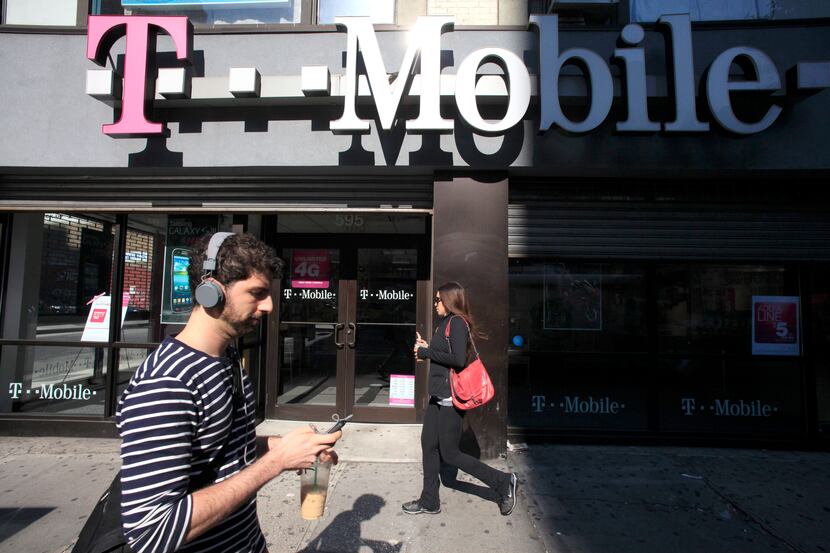 A man uses a cellphone as he passes a T-Mobile store in New York.