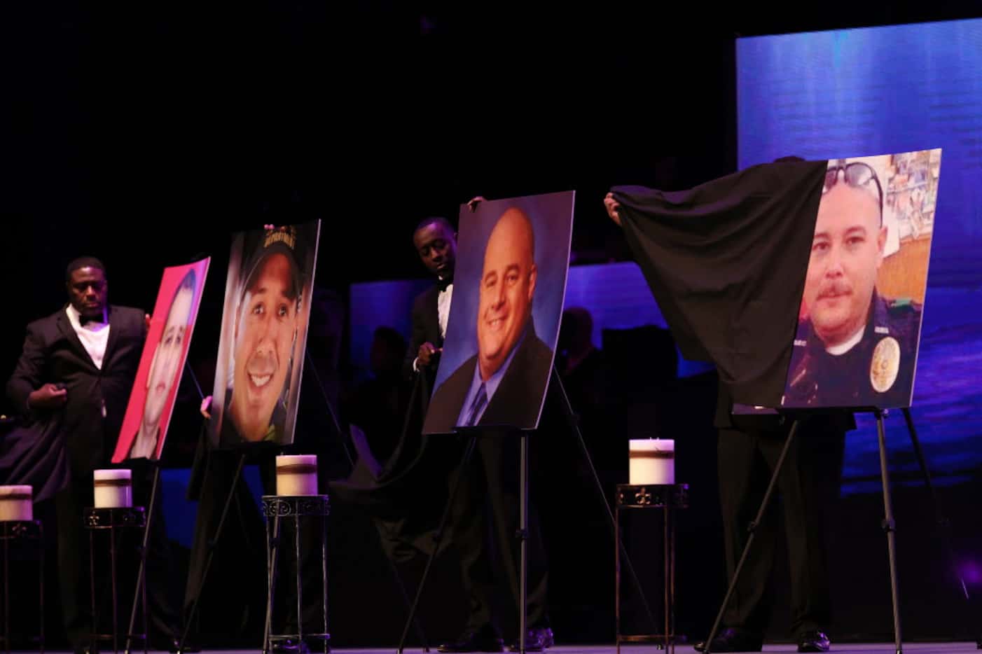 Worshipers unveil photos of the fallen officers at The Potter's House on Sunday. 
