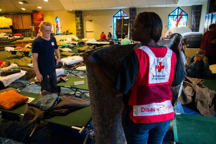 Red Cross volunteer Kainoa Flemons folds a blanket for evacuees at Woodcrest Church after...