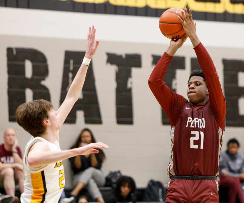 Plano forward Justin McBride (21) shot over Frisco Memorial forward Cooper Mendel (24)...