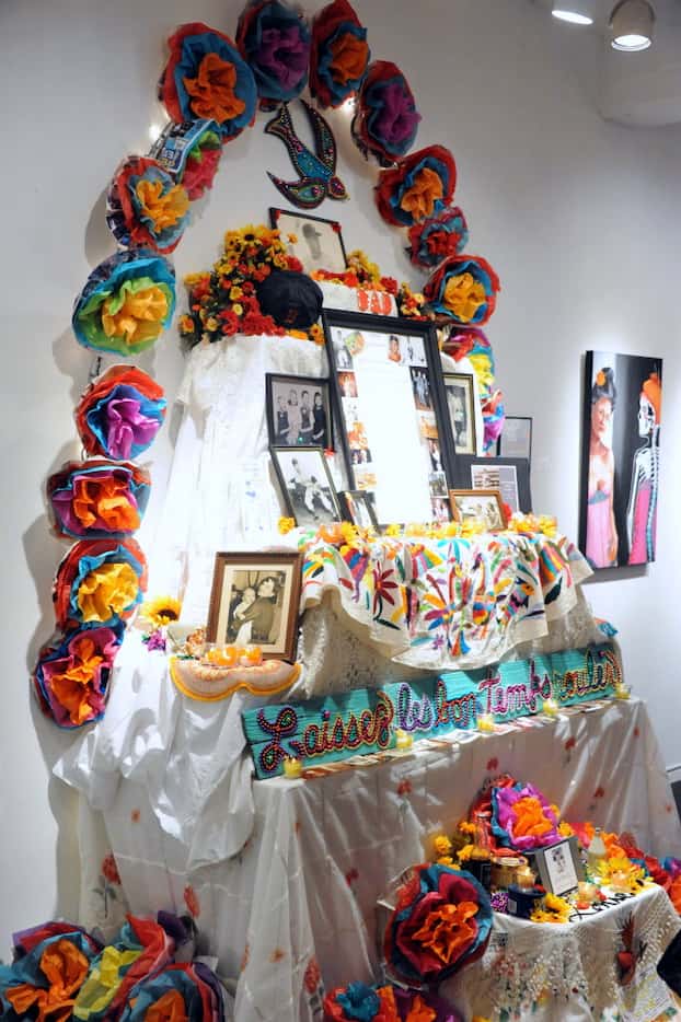 A Dia de los Muertos shrine displays photographs, baseball hats and colorful flowers at the...