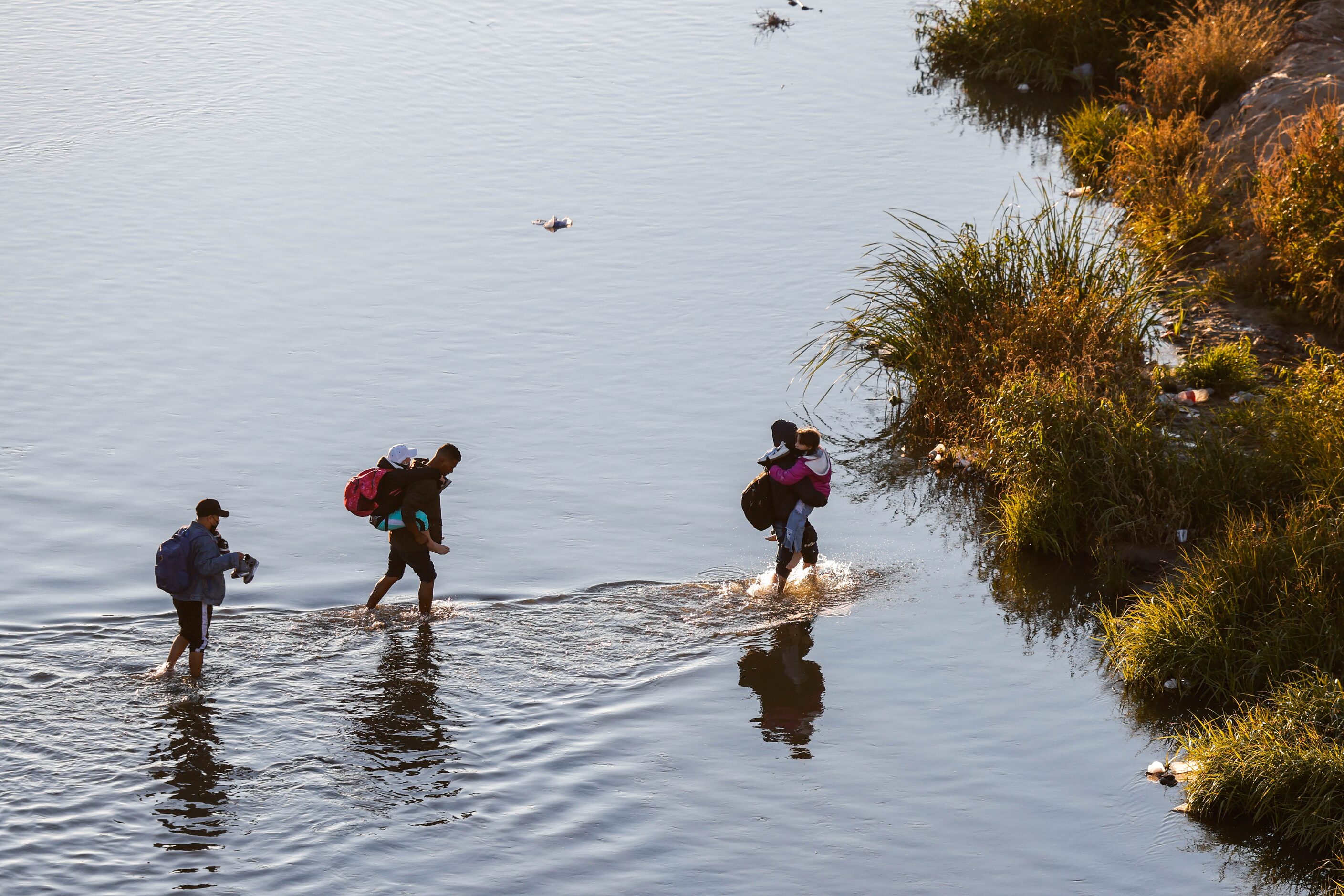 Migrants cross the Rio Grande river and US-Mexico border into El Paso, Texas as seen from...