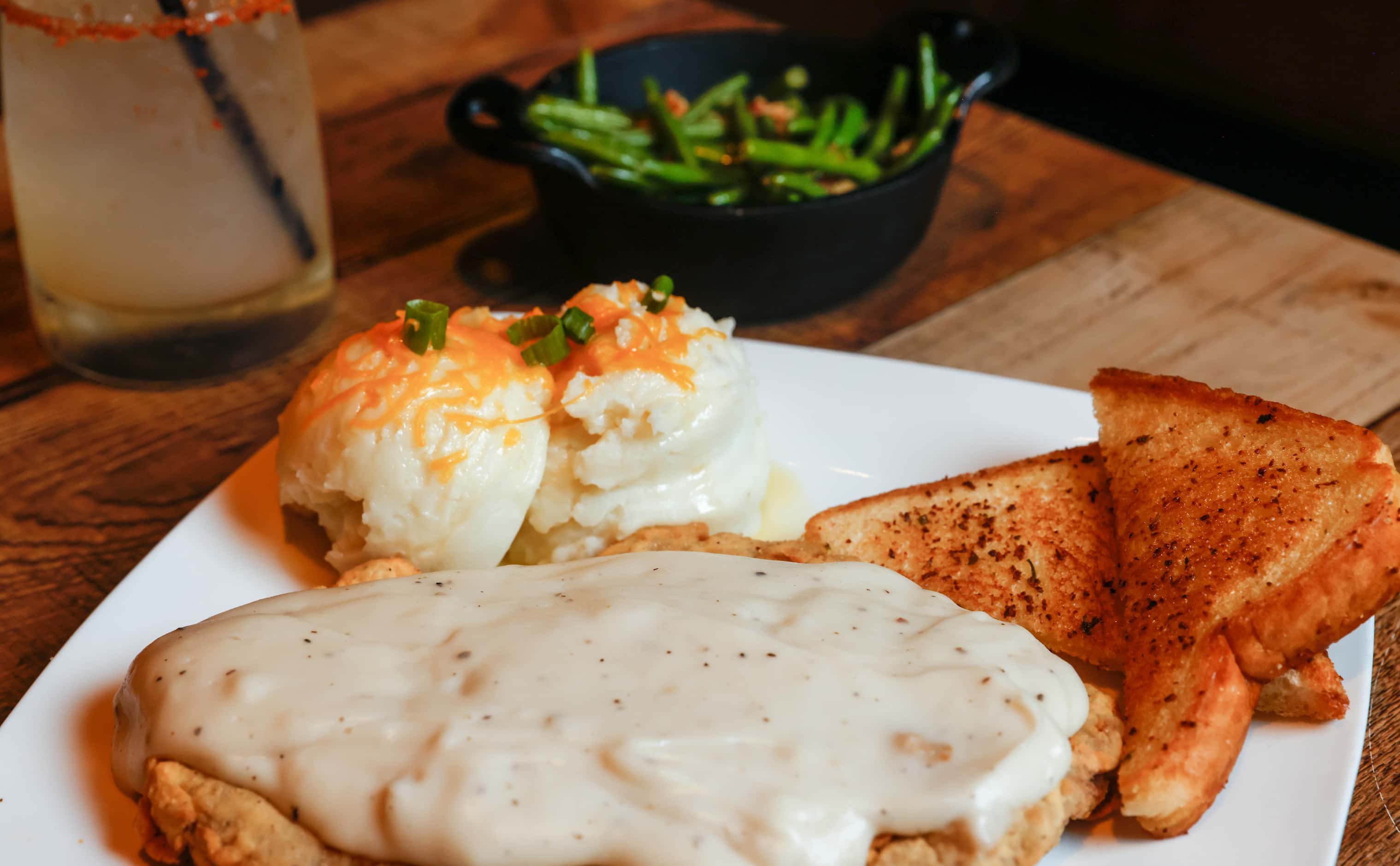 Kuntry & Wistern Fried Steak is served with mashed potatoes and bacon-sauteed green beans at...