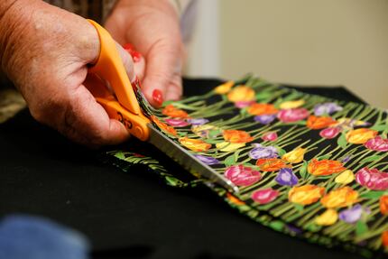 Mirchelle Louis, chief executive of Cancer Support Community North Texas, cuts fabric for a...