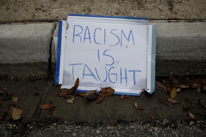  A sign that reads "Racism is Taught" sits on the curb in front of the Rice family's Dallas...