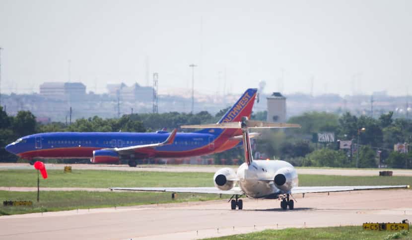  A Delta Airlines jet taxis behind a Southwest Airlines jet in this June photo at Dallas...
