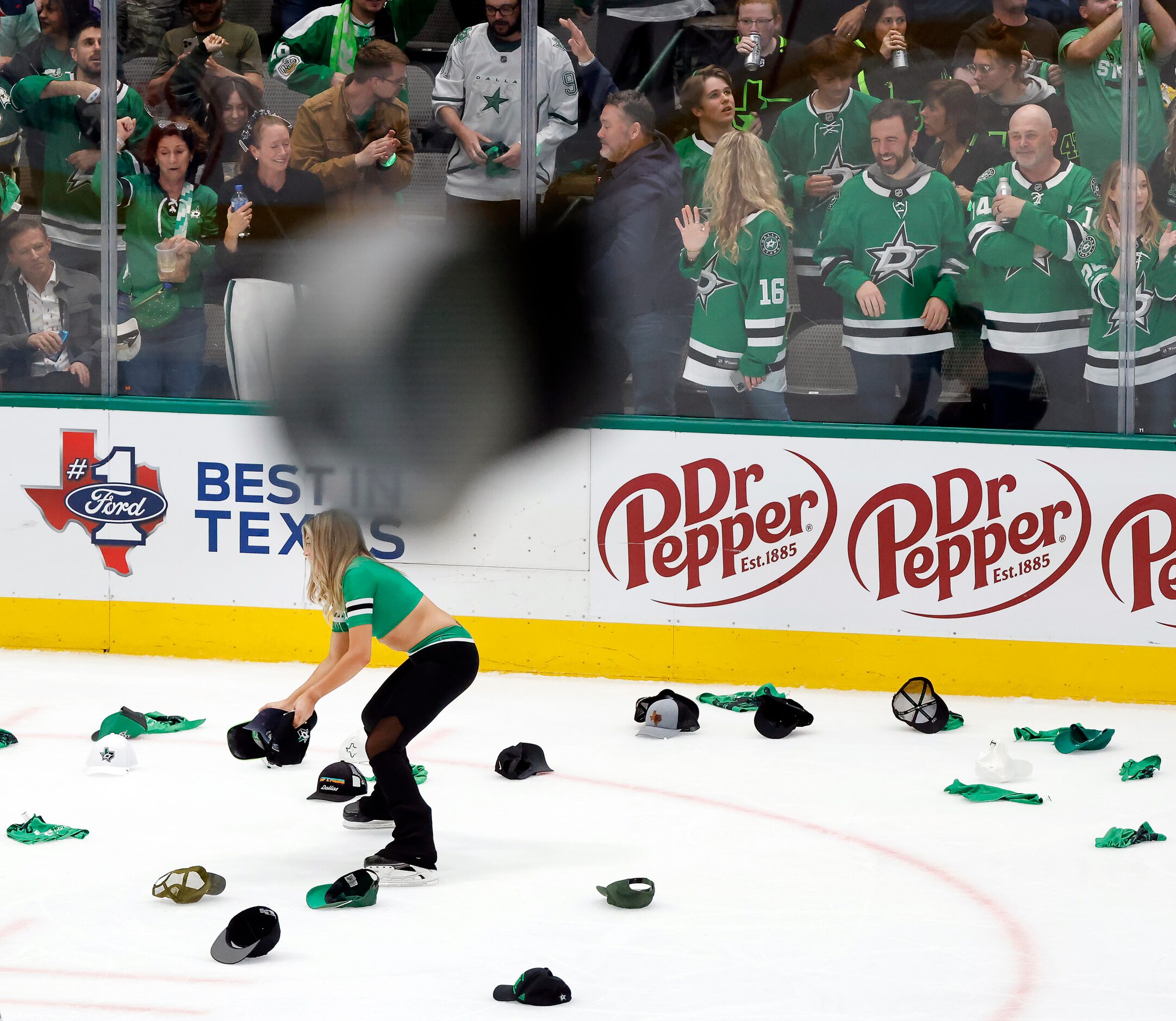 A Dallas Stars Ice Girl collects hats thrown on the ice following Dallas Stars center Joe...