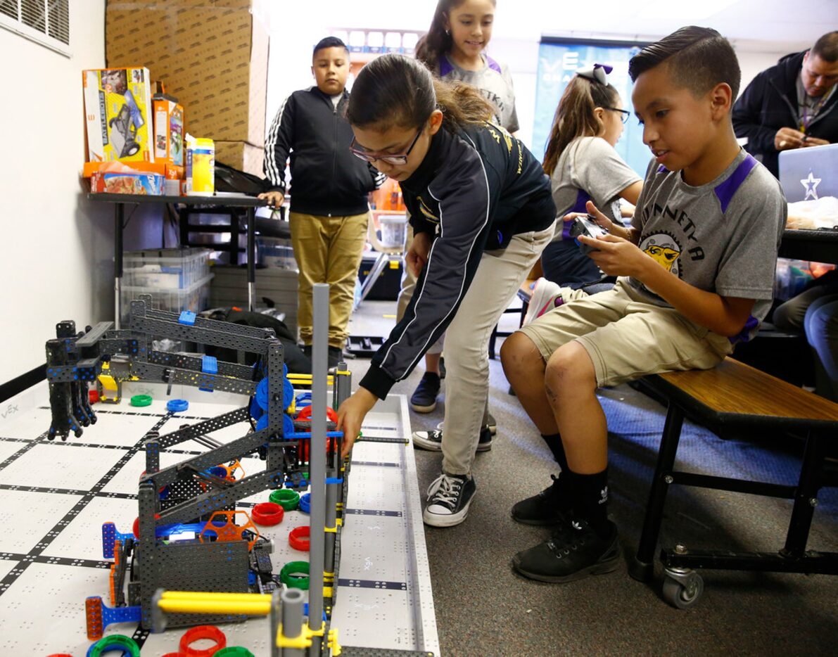 Joshua Salazar (right with remote) and Cassandra Gayton use robots to pick up points as they...