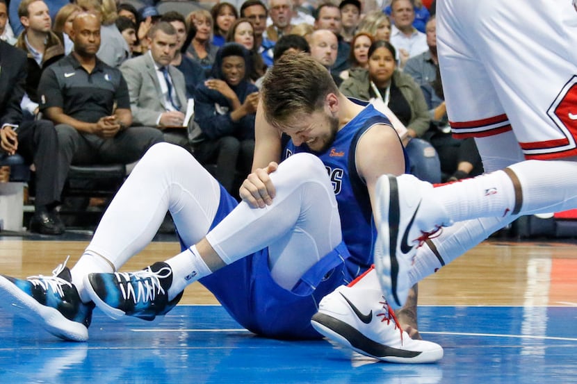 Dallas Mavericks guard Luka Doncic (77) grabs his leg after falling in the lane in the...