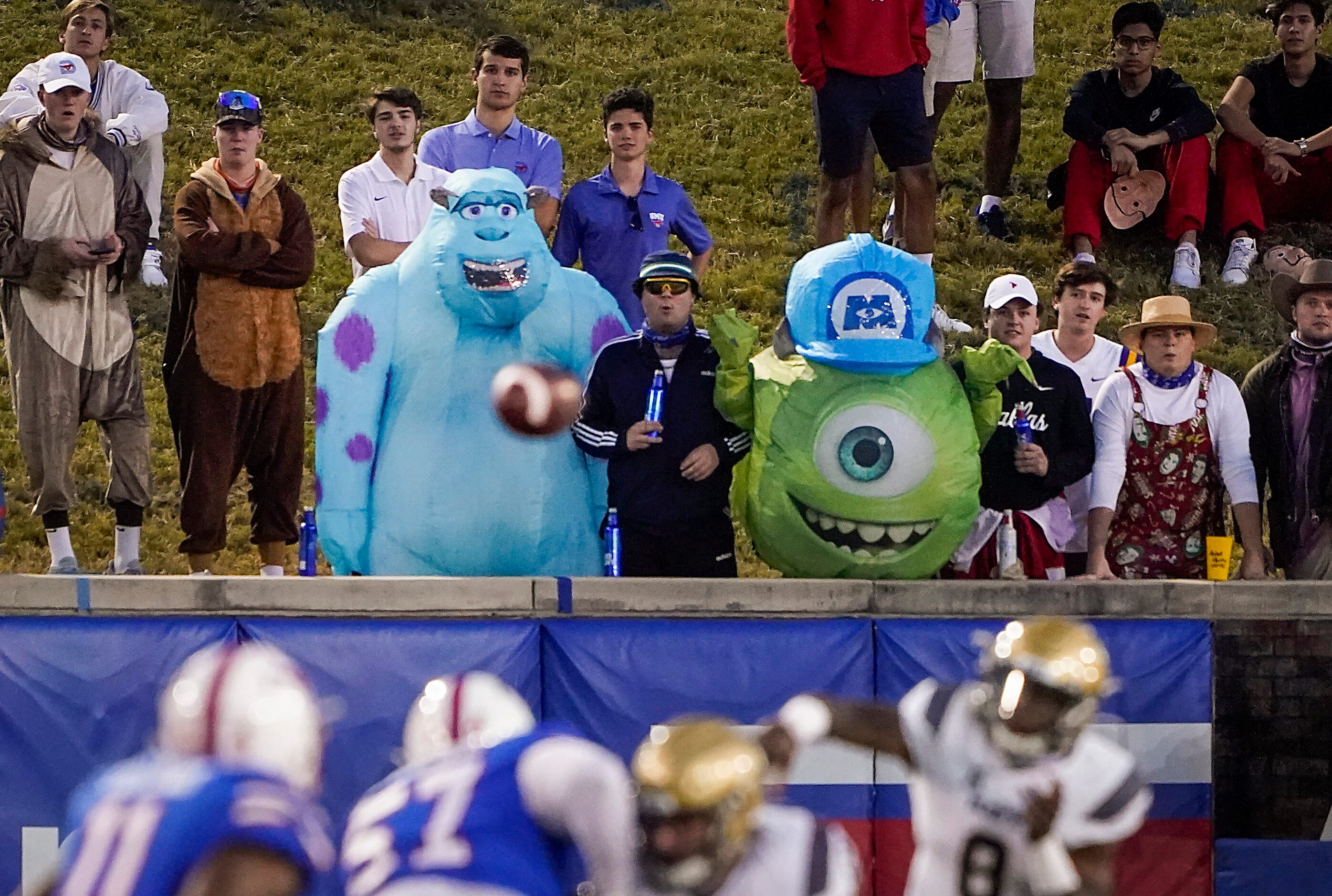 Costumed SMU fans watch as Navy quarterback Dalen Morris (8) throws a pass during the first...