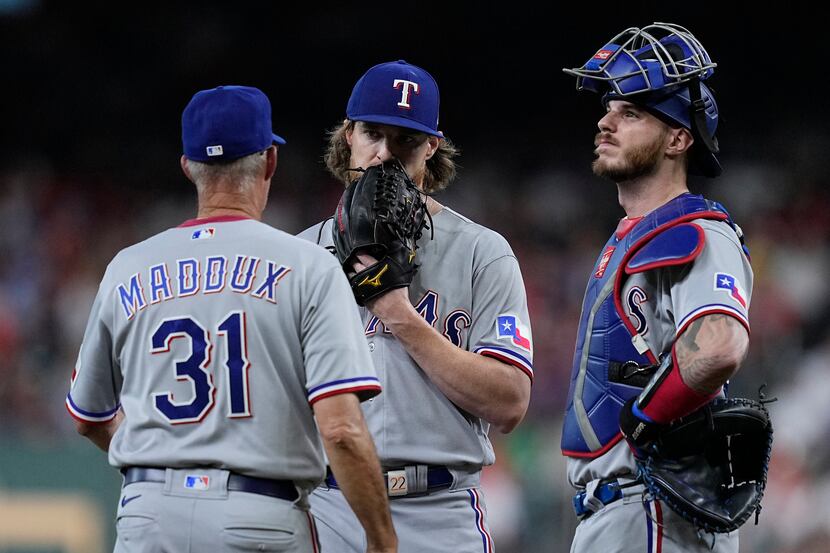 Texas Rangers starting pitcher Jon Gray, center, gets a mound visit from pitching coach Mike...
