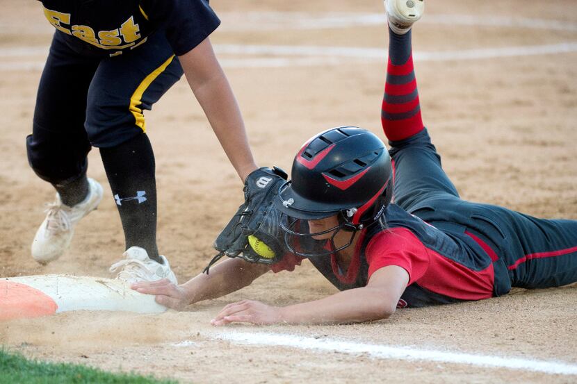 Flower Mound Marcus senior catcher Kendra Hess (13) dives safely back to first base ahead of...