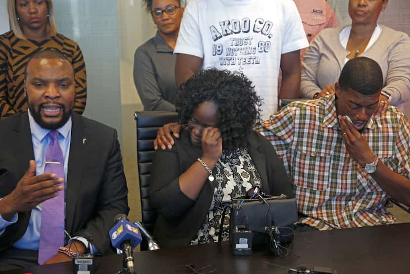 Charmaine and Odell Edwards wipe away tears as their attorney, Lee Merritt, talks Monday...
