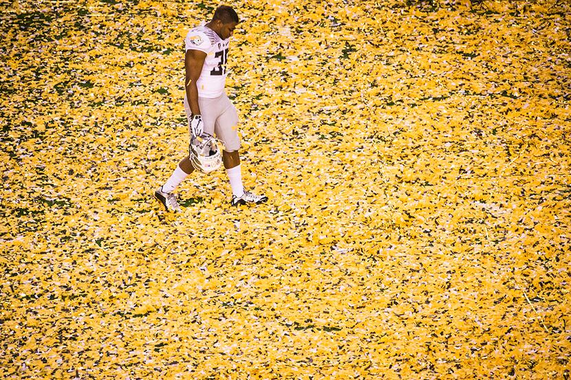  Oregon Ducks running back Kani Benoit walks off the field through a blanket of confetti...