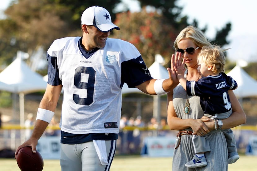 Dallas Cowboys quarterback Tony Romo (9) plays with his son Hawkins Romo, 1, as his wife...