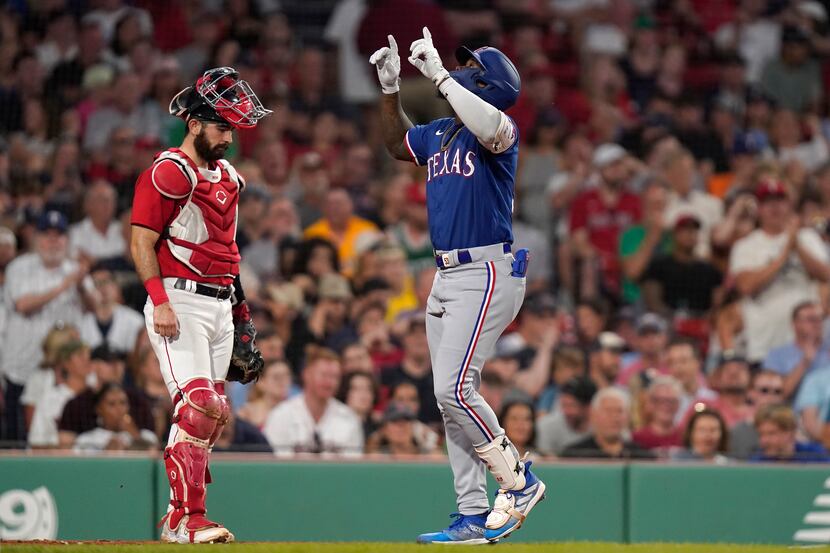 Texas Rangers Adolis Garcia, right, celebrates in front of Boston Red Sox's Connor Wong,...