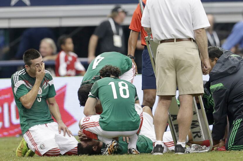 Mexico players gather around Luis Montes (20) after he broke his right leg in the first half...