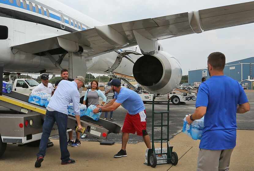 l jugador de los Mavericks, J.J. Barea (der.) ayuda a cargar de vituallas el avión de los...