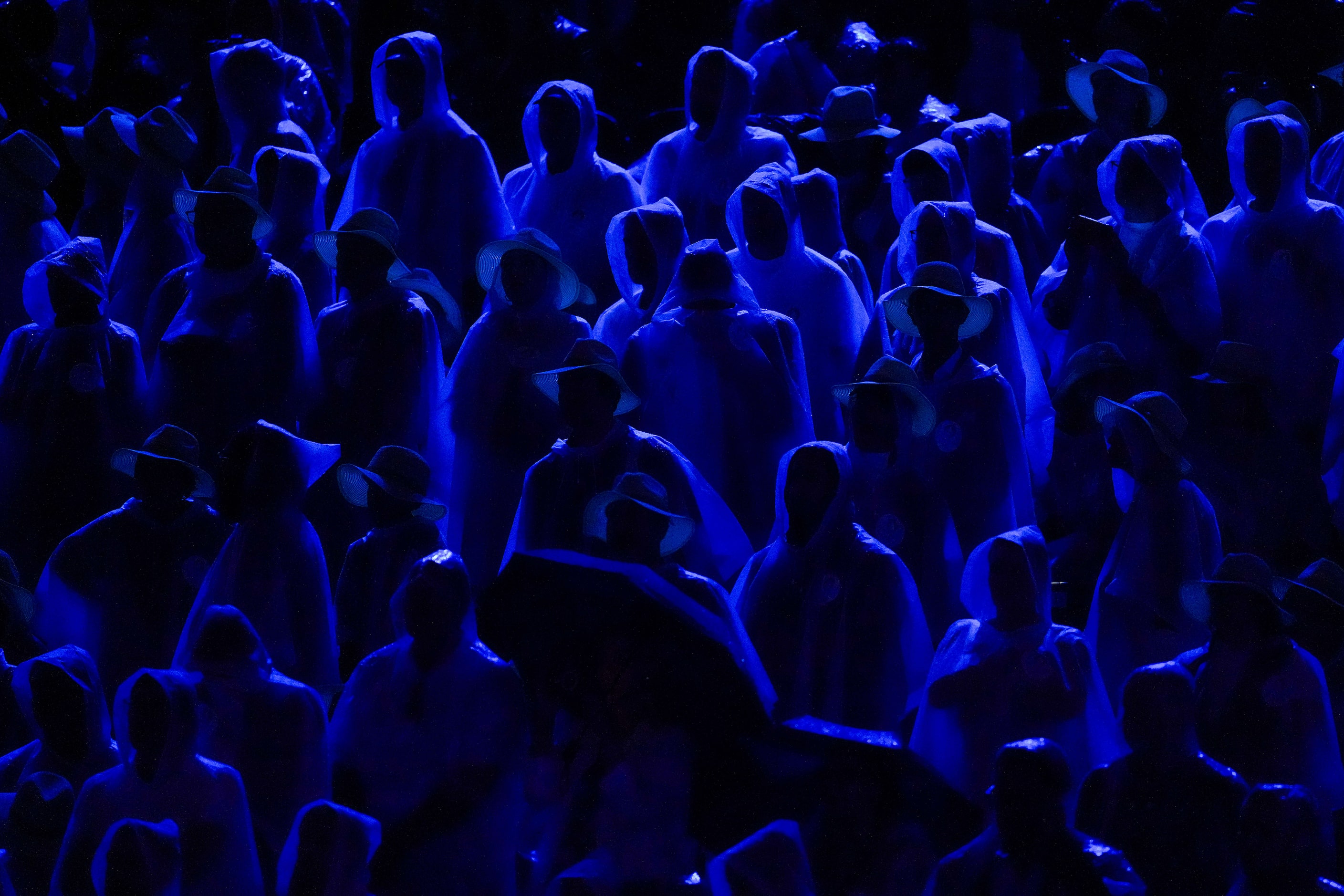 People huddle under rain ponchos during opening ceremonies for the 2024 Summer Olympics on...