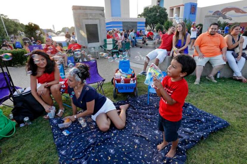 
Families enjoy the evening before the Fourth of July fireworks in Fair Park during last...