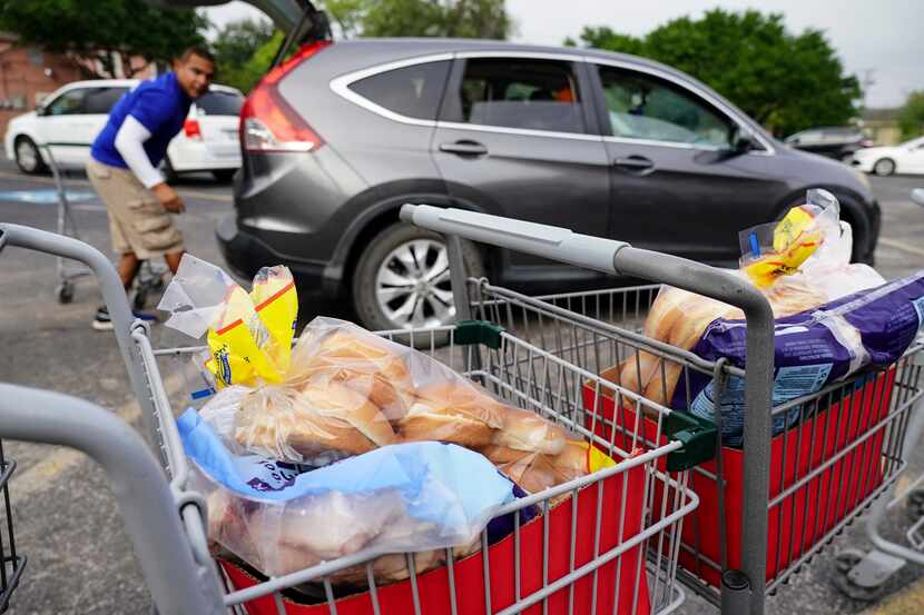 Boxes of bread and baked goods are set out in carts for volunteers to load into vehicles at...