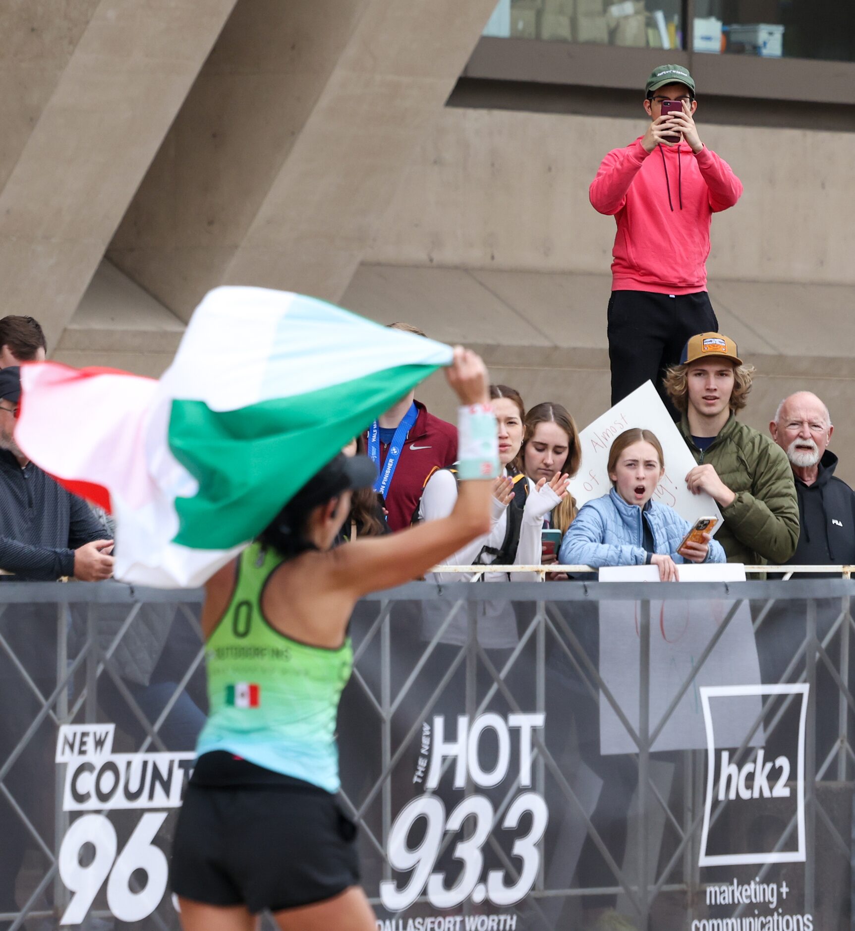 The crowd cheers for marathon and ultra-marathon runners as they near the finish line of the...