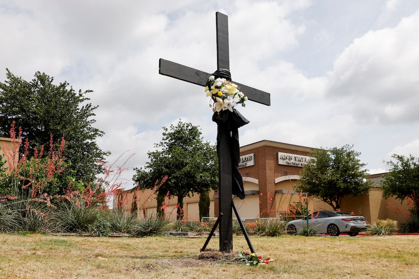 A lone cross stands where a large memorial for victims of the Allen Premium Outlets shooting...