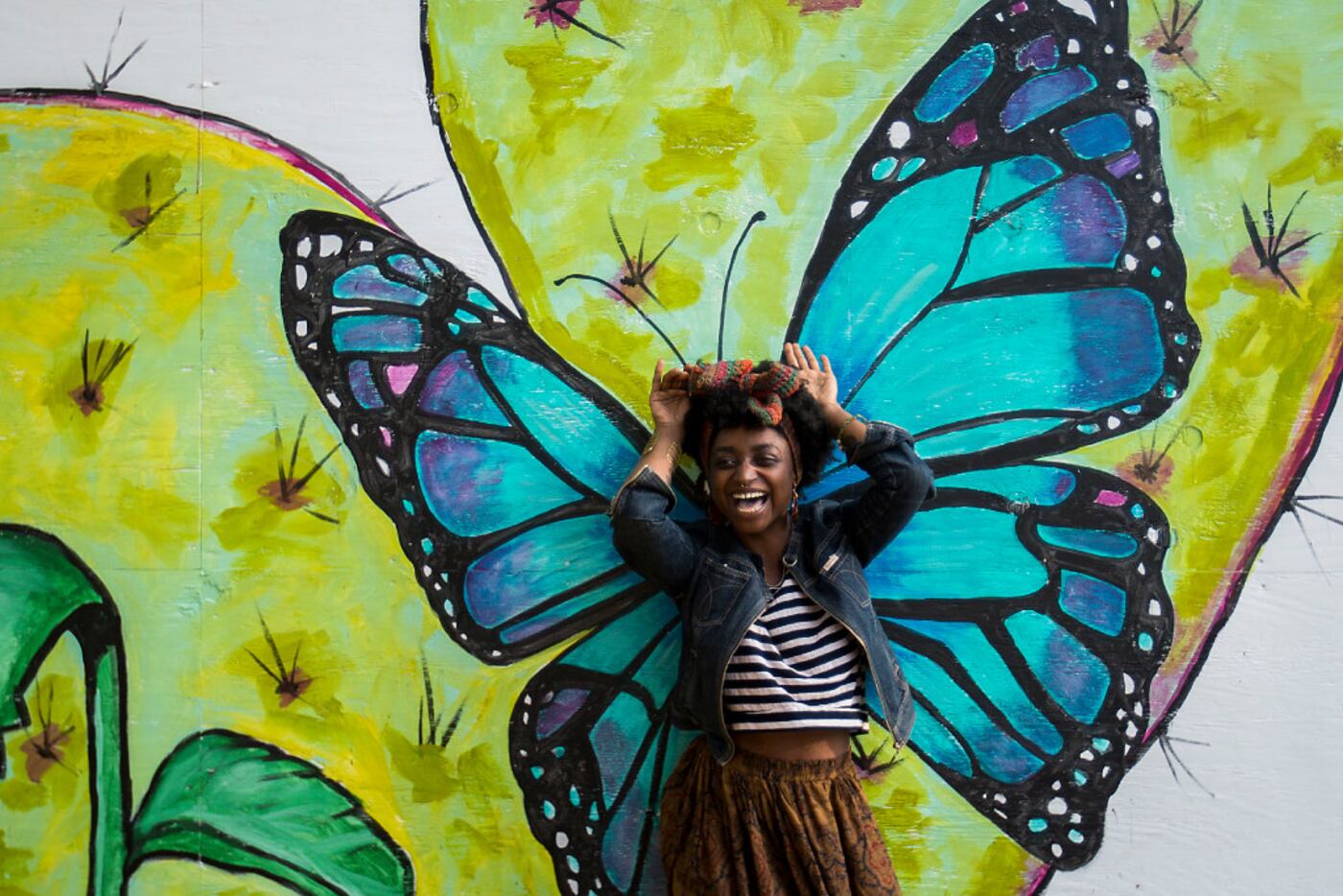Essence Mahara poses for a photo against a backdrop of paintings of flora and fauna at...