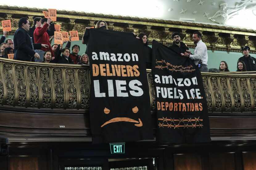 Protesters unfurl anti-Amazon banners from the balcony of a hearing room during a New York...
