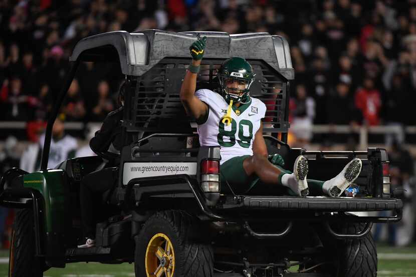 Baylor tight end Drake Dabney (89) raises his hand as he is driven off the field after a leg...