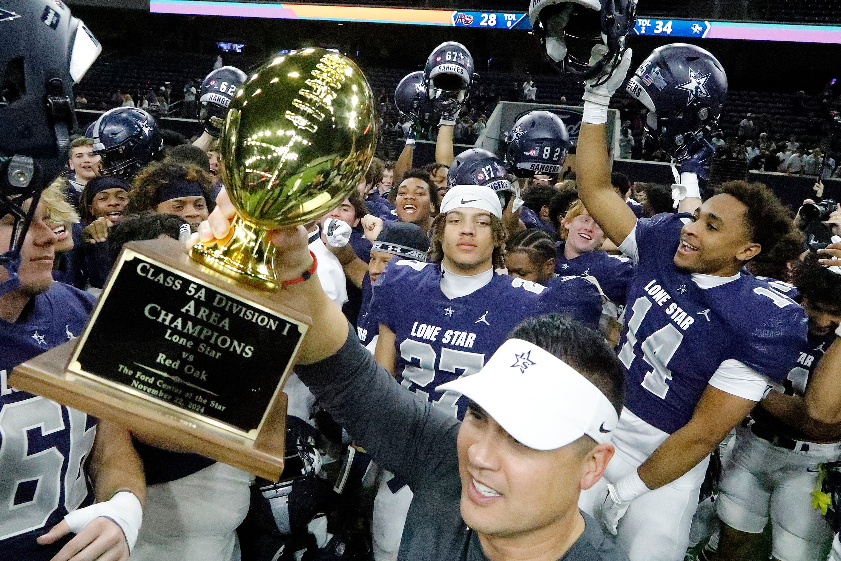 Lone Star High School head coach Jeff Rayburn holds up the area championship trophy after...