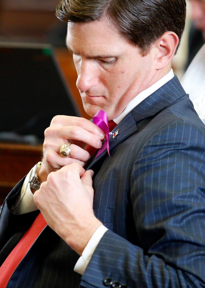 Rep. Brooks Landgraf, R-Odessa, pins a purple ribbon on his jacket honoring Linda...