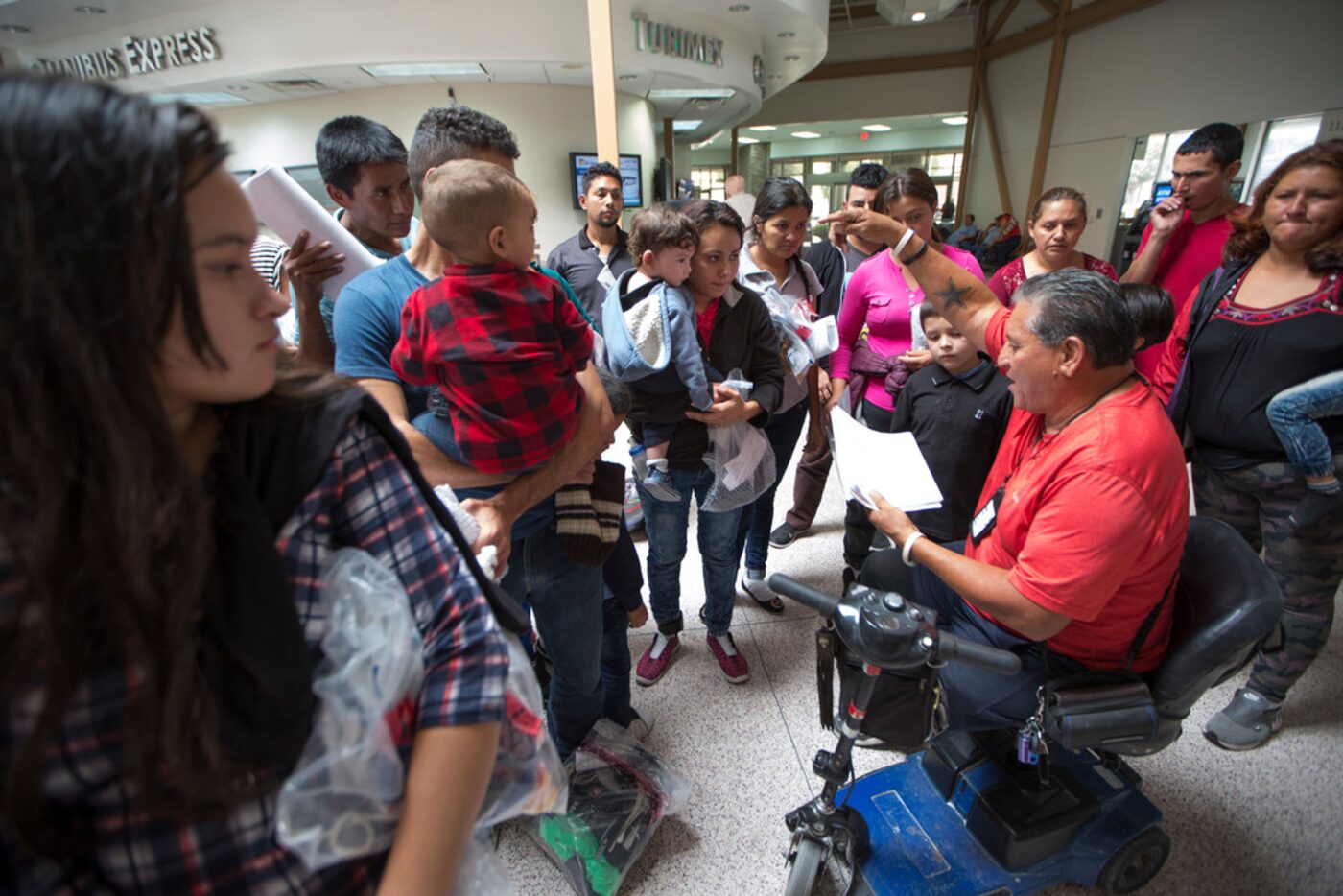 Immigrants wait to be picked up by volunteers from Catholic Charities of the Rio Grande...