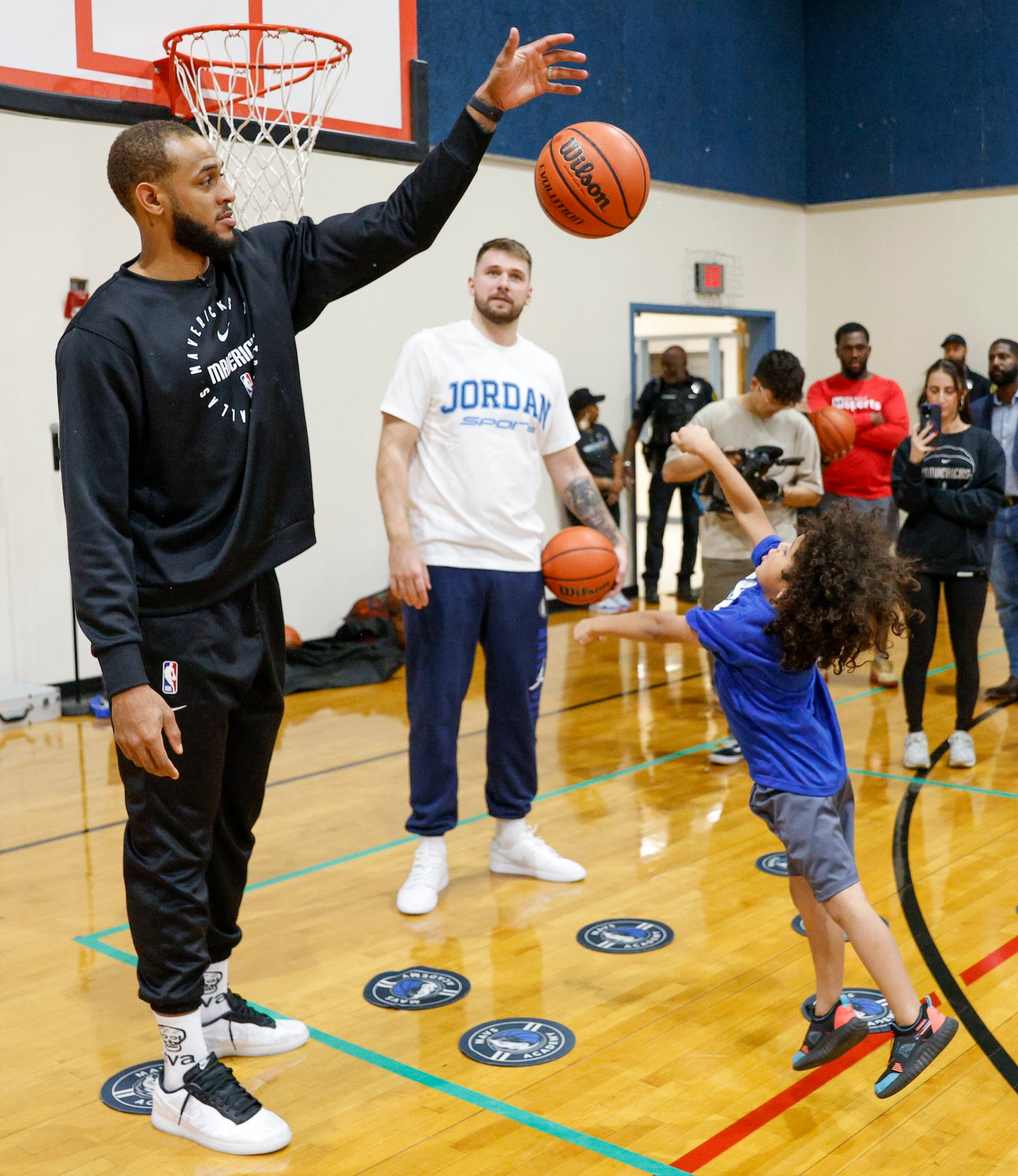 Dallas Mavericks center Daniel Gafford blocks a child’s shot alongside guard Luka Doncic...