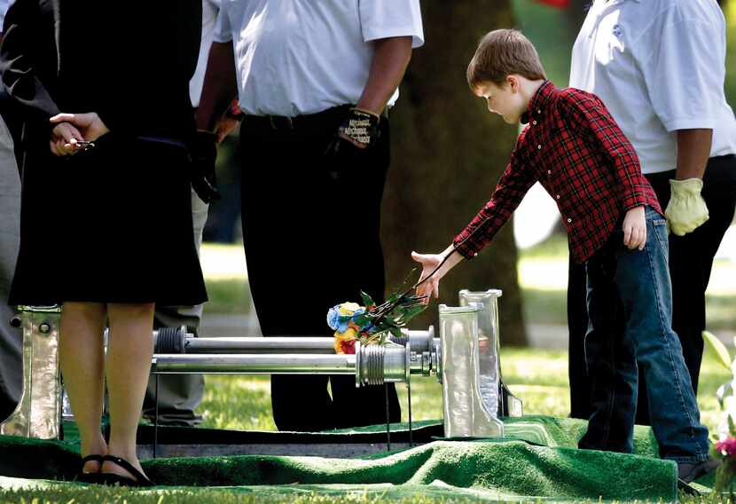 Magnus Ahrens, 8, son of fallen Dallas Senior Cpl. Lorne Ahrens, dropped flowers on his...