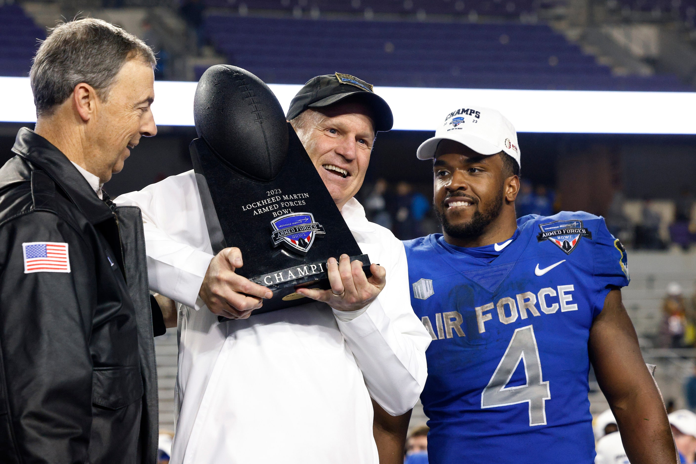 Air Force head coach Troy Calhoun raises the Armed Forces Bowl championship trophy alongside...