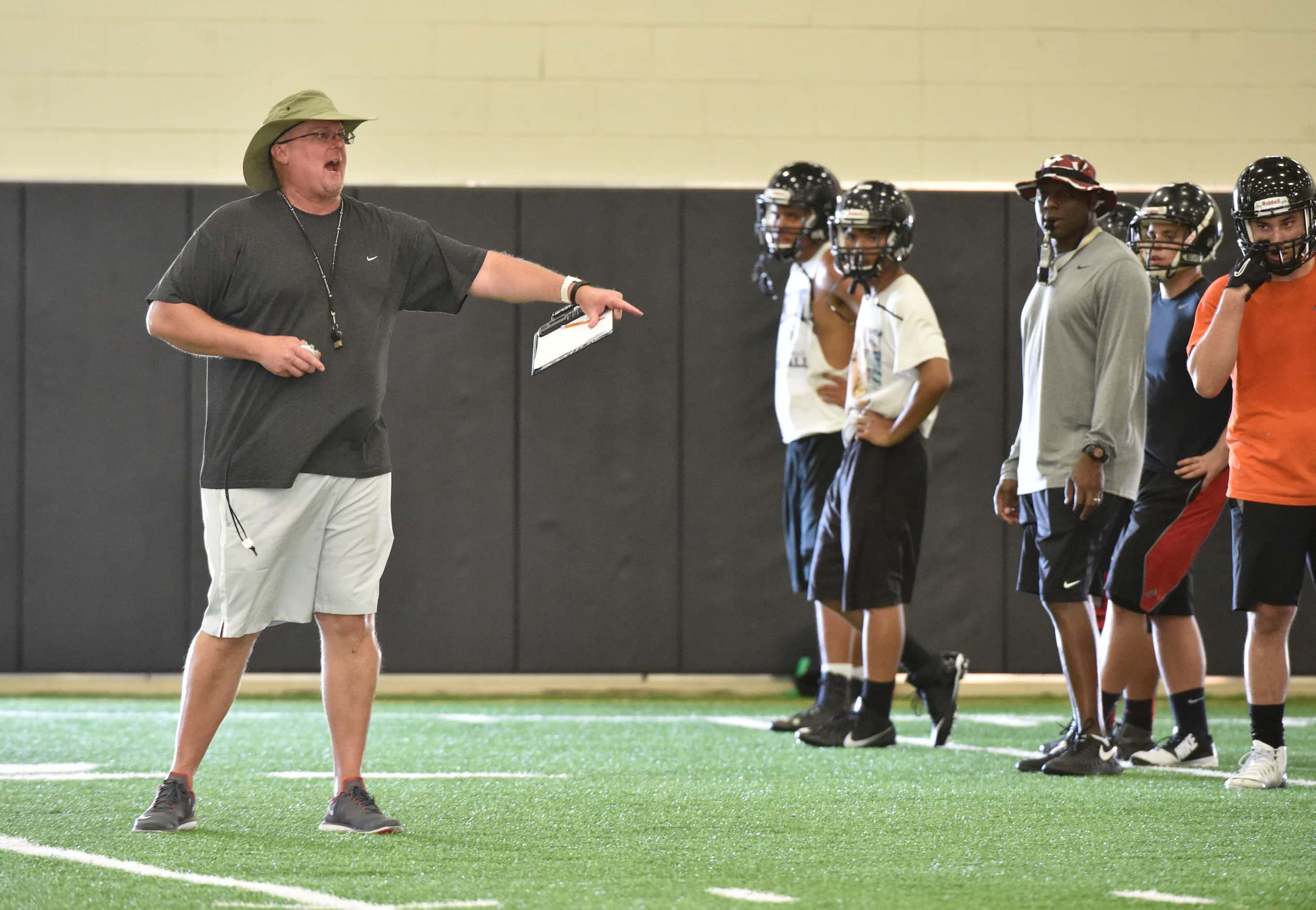 Coach Chris Jensen gives direction to his team during Euless Trinity's first day of football...