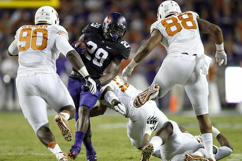 TCU running back Jordan Moore (29) is turned around by Texas defensive tackle Chris Whaley...