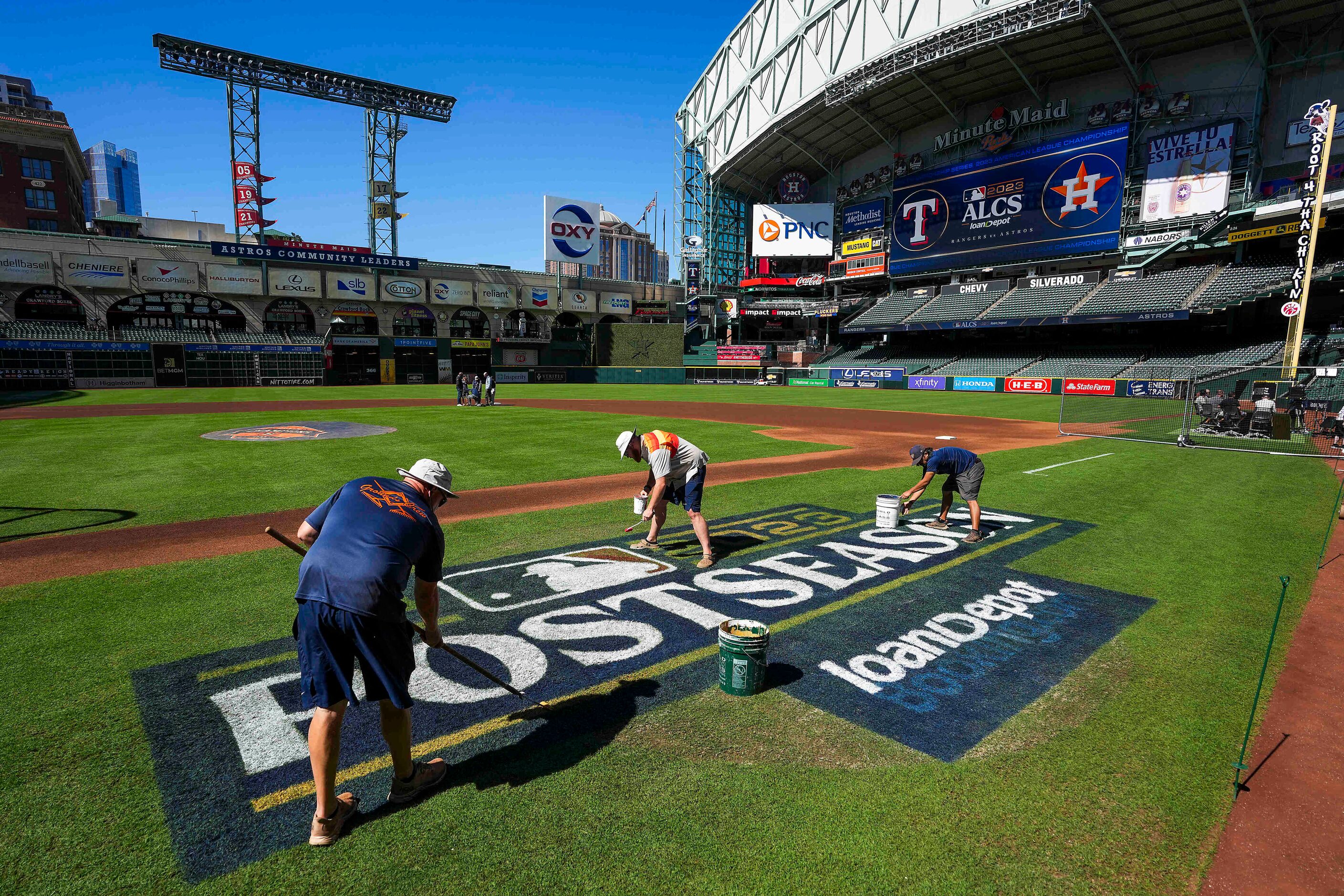 Groundskeepers paint a logo on the field prior to a Texas Rangers workout in preparation for...