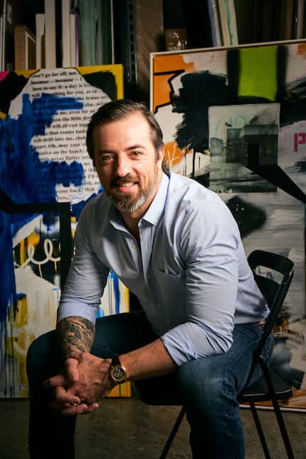 Man sits on a chair in front of graffiti art in a studio.