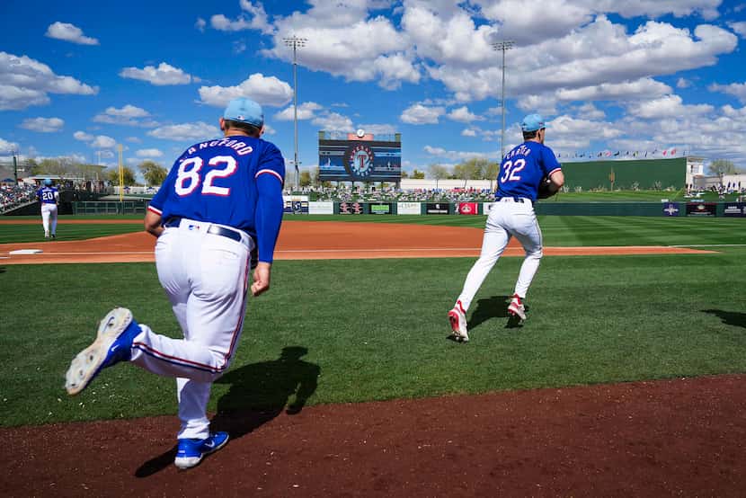 Texas Rangers outfielders Evan Carter (32) and Wyatt Langford (82) take the field for a...