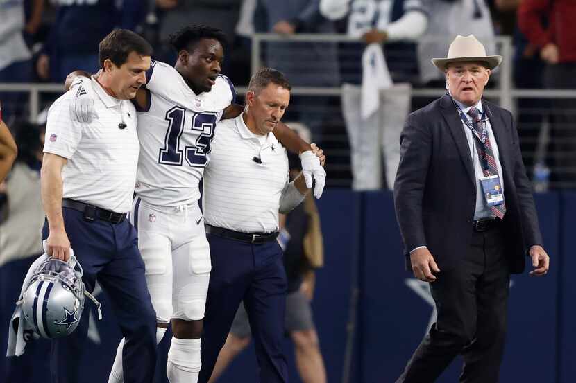Dallas Cowboys wide receiver Michael Gallup (13) is helped off the field by medical staff in...