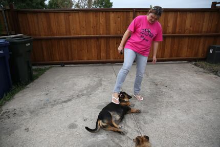 Martha Salazar plays with her dog Princess outside her newly renovated home that was damaged...