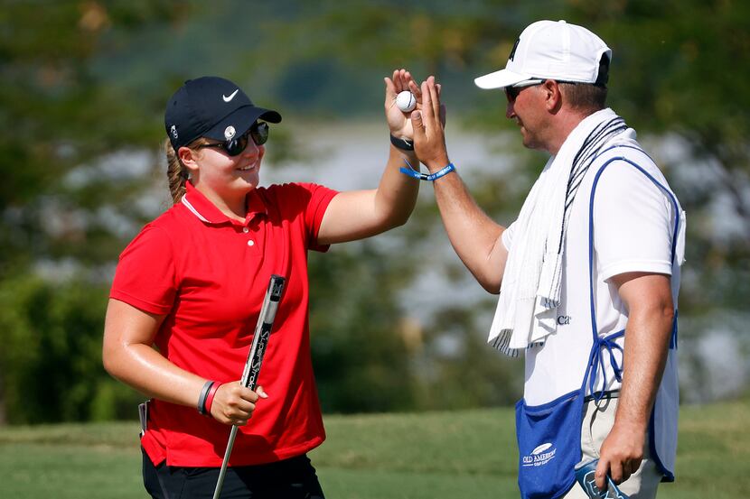 Amateur golfer Avery Zweig, 14, of McKinney (left) receives a high-five from her caddie Adam...